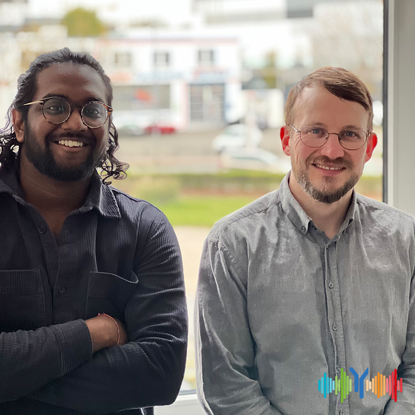 Hari, our podcast sidekick, and Brett, HSRW&#039;s university translater and department head, standing next to each other and brightly smiling into the camera