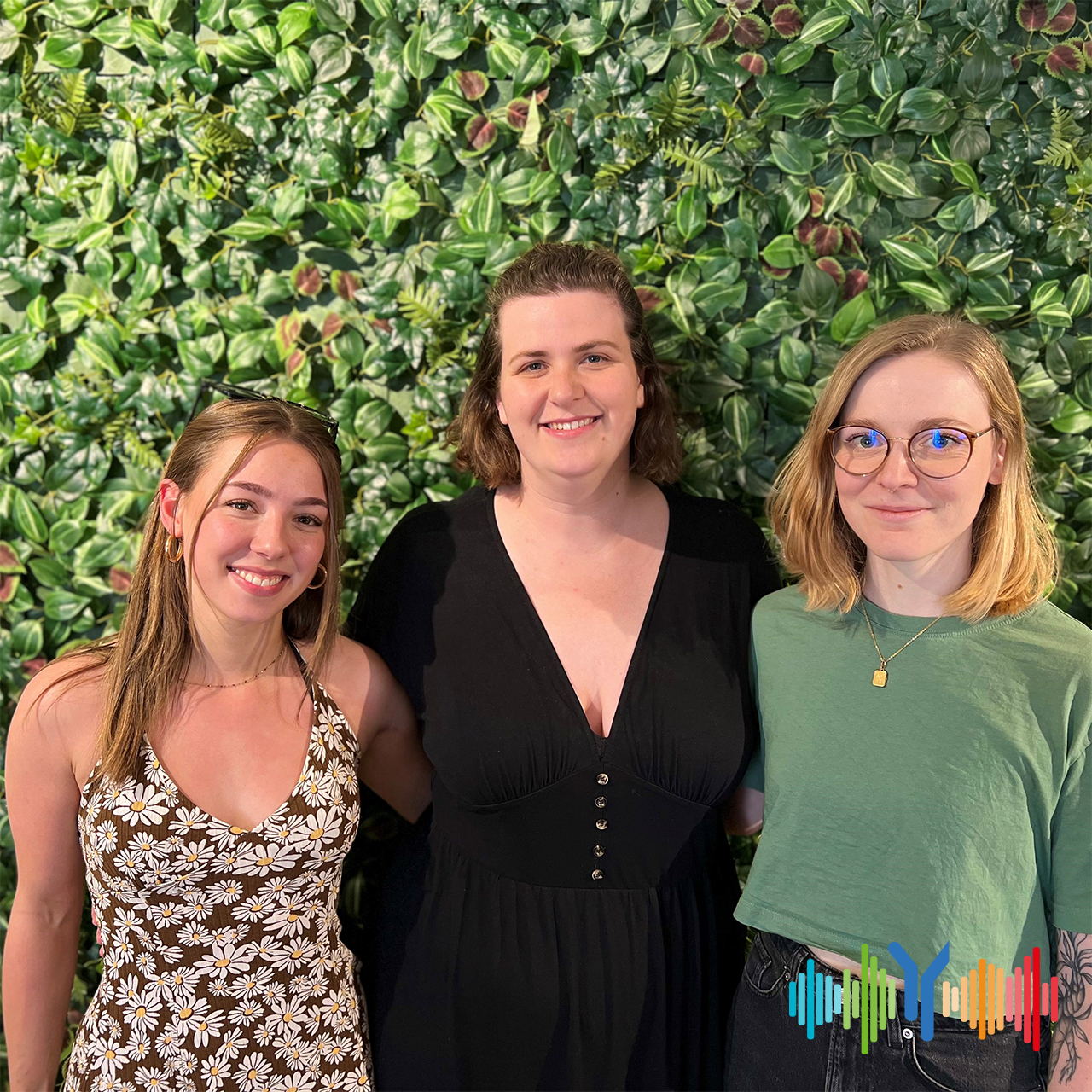 Three passionate young friends, women and students are standing in front of a plant-covered wall in their self-run café in Kleve city