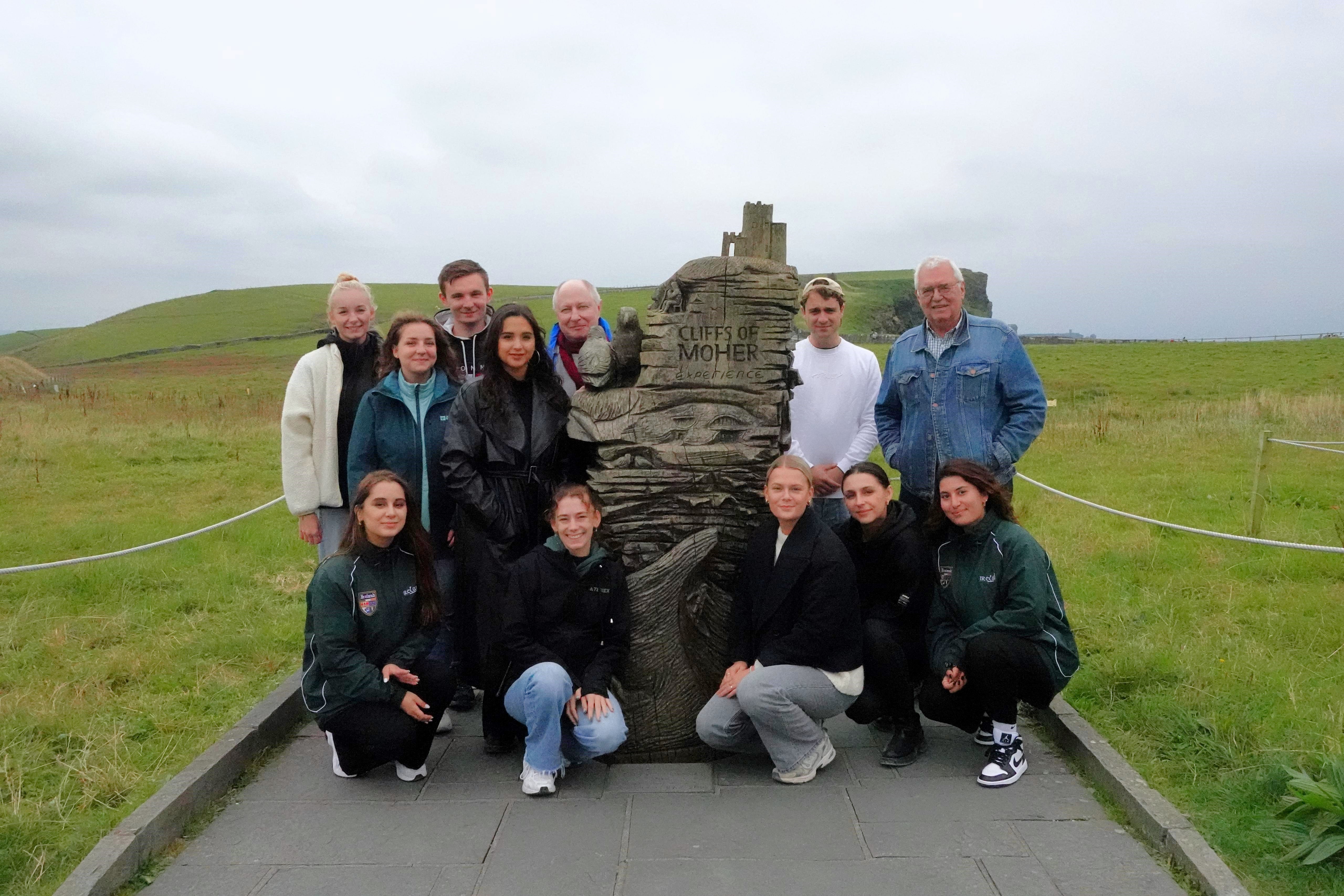 Prof. Dr. Dirk Reiser und Wissenschaftliche Mitarbeiterin Ilona Benkendorf stehen mit Studierenden um ein Denkmal mit der Aufschrift 