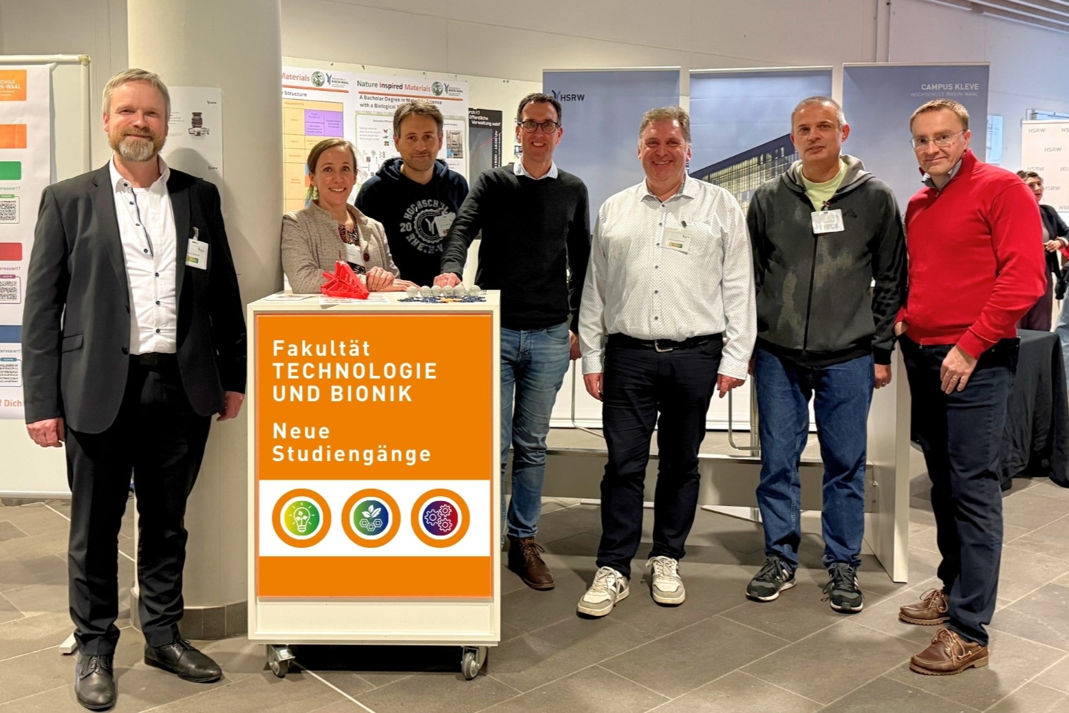 7 Mitglieder der Fakultät Technologie und Bionik stehen in der ProbierDich-Lounge bei den „Wochen der Studienorientierung 2025“  nebeneinander beim Messecounter der Fakultät