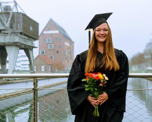 Das Foto zeigt unsere Absolventin Mirjam Schaar auf dem Campus bei ihrer Graduation
