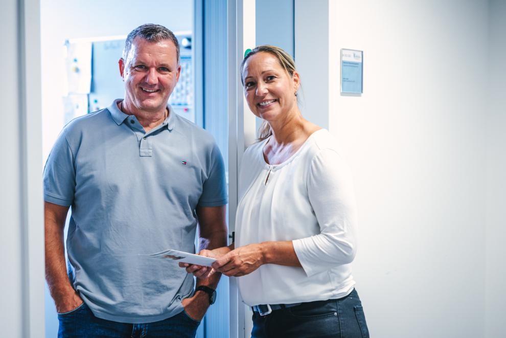 Von links nach rechts zu sehen sind ein Mann und eine Frau. Sie bilden das BEM-Team (Betriebliche Wiedereingliederung).