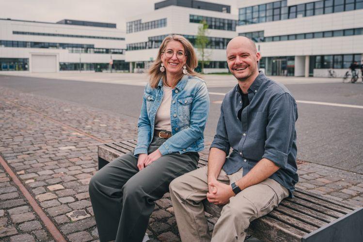 Zwei Personen sitzen auf einer Bank auf dem Campus Kleve