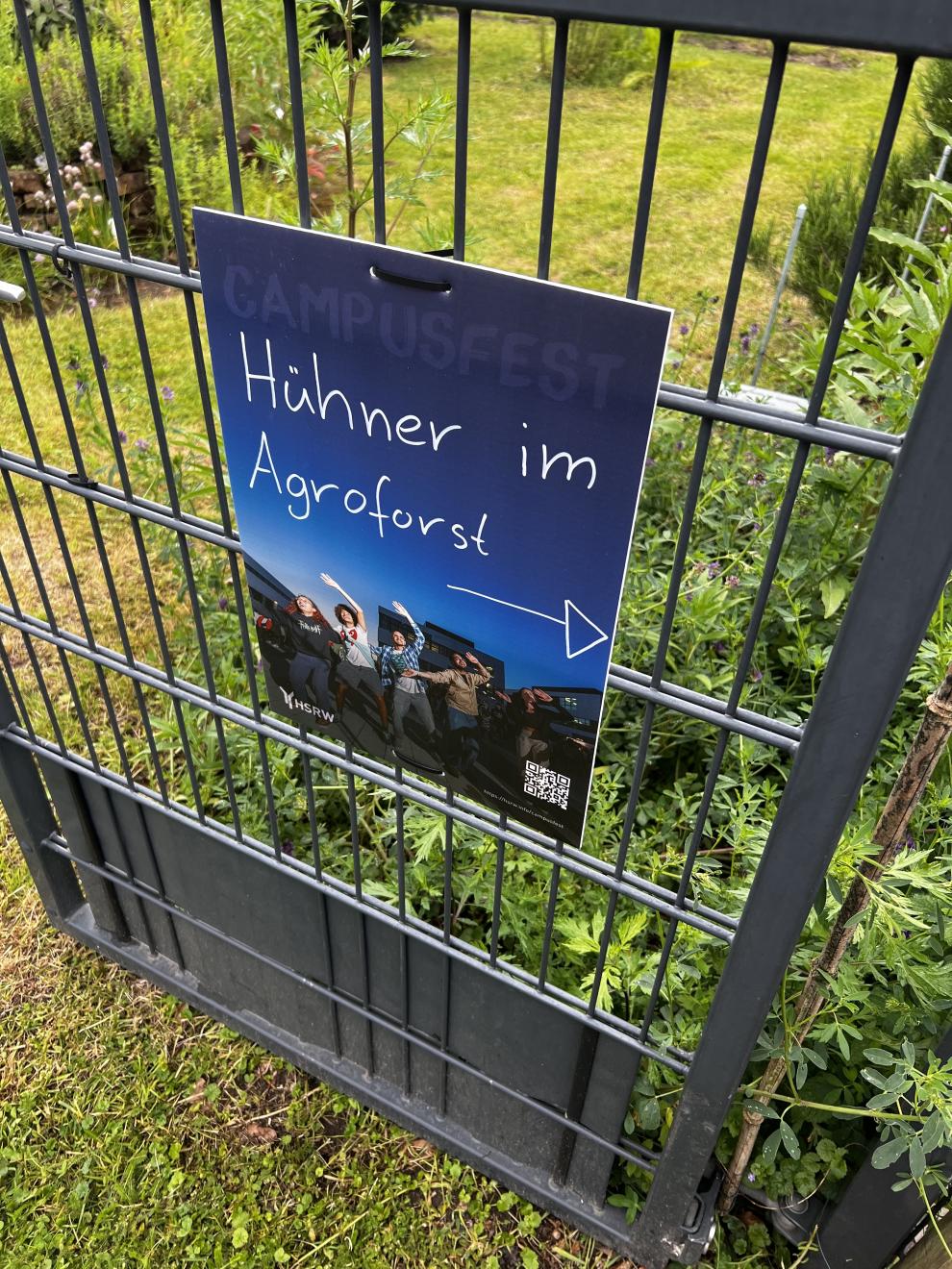 Ein Schild am Zaun informiert über Hühner im Agroforst. Das Schild ist Teil der Präsentation über nachhaltige Landwirtschaft und Tierhaltung.