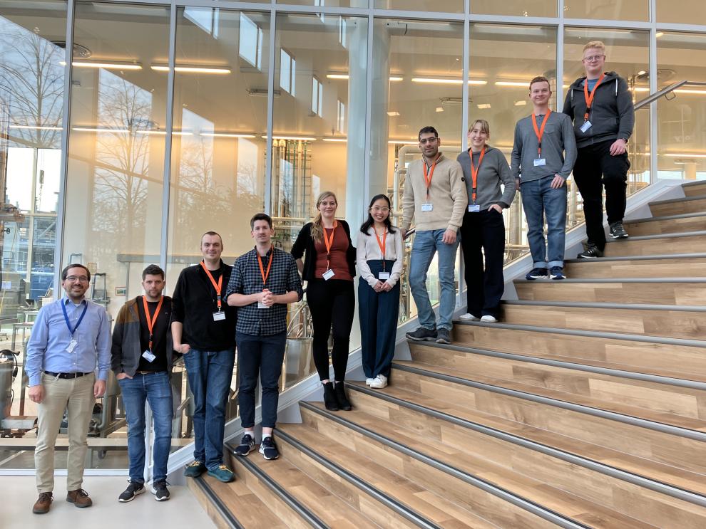 Eine Gruppe von Menschen, Studierende und Mitarbeiter der HSRW, steht auf einer Treppe, als sie die Firma Danone besuchen.
