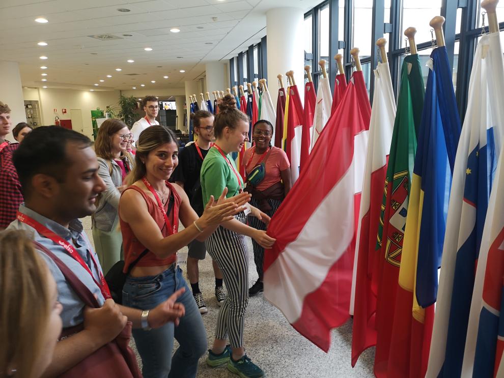 Eine Gruppe von Studierenden steht in einem Gebäude mit zahlreichen Fahnen im Hintergrund. Hierbei handelt es sich um den Besuch bei der Europäischen Lebensmittelsicherheitsbehörde (EFSA) in Parma, wo die Studierenden eine Einführung in die Arbeitsweise der Behörde erhielten und über aktuelle Herausforderungen in der Lebensmittelsicherheit diskutierten.