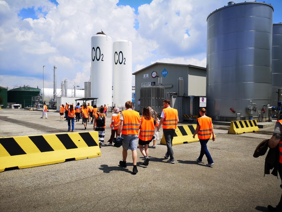 Die Gruppe von Studierenden in Sicherheitswesten bewegt sich in einem Industriekomplex. Dieses Bild stammt vom Besuch bei Caviro Company in Faenza stammen, besonders von der Besichtigung der Produktionsstätte in Forli.