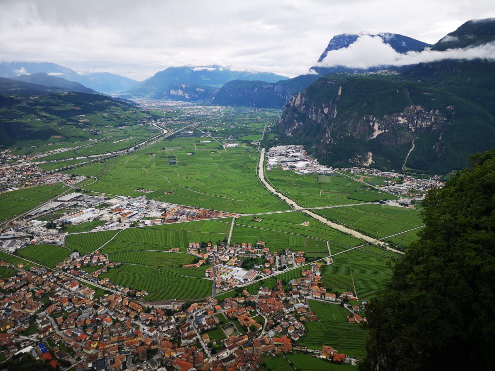 Eine weite Landschaft mit grünen Feldern und Bergen im Hintergrund. Dieses Bild ist während der Fahrt durch die Po-Ebene in die Alpen aufgenommen worden, auf dem Weg nach Trient.
