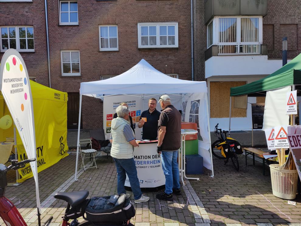 Mehrere Personen unterhalten sich draußen vor einem Pavillon.