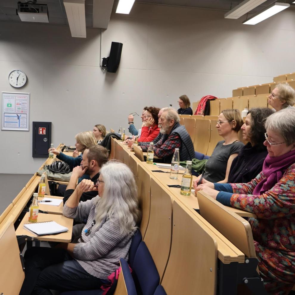 Mehrere Menschen sitzen in einem Hörsaal.