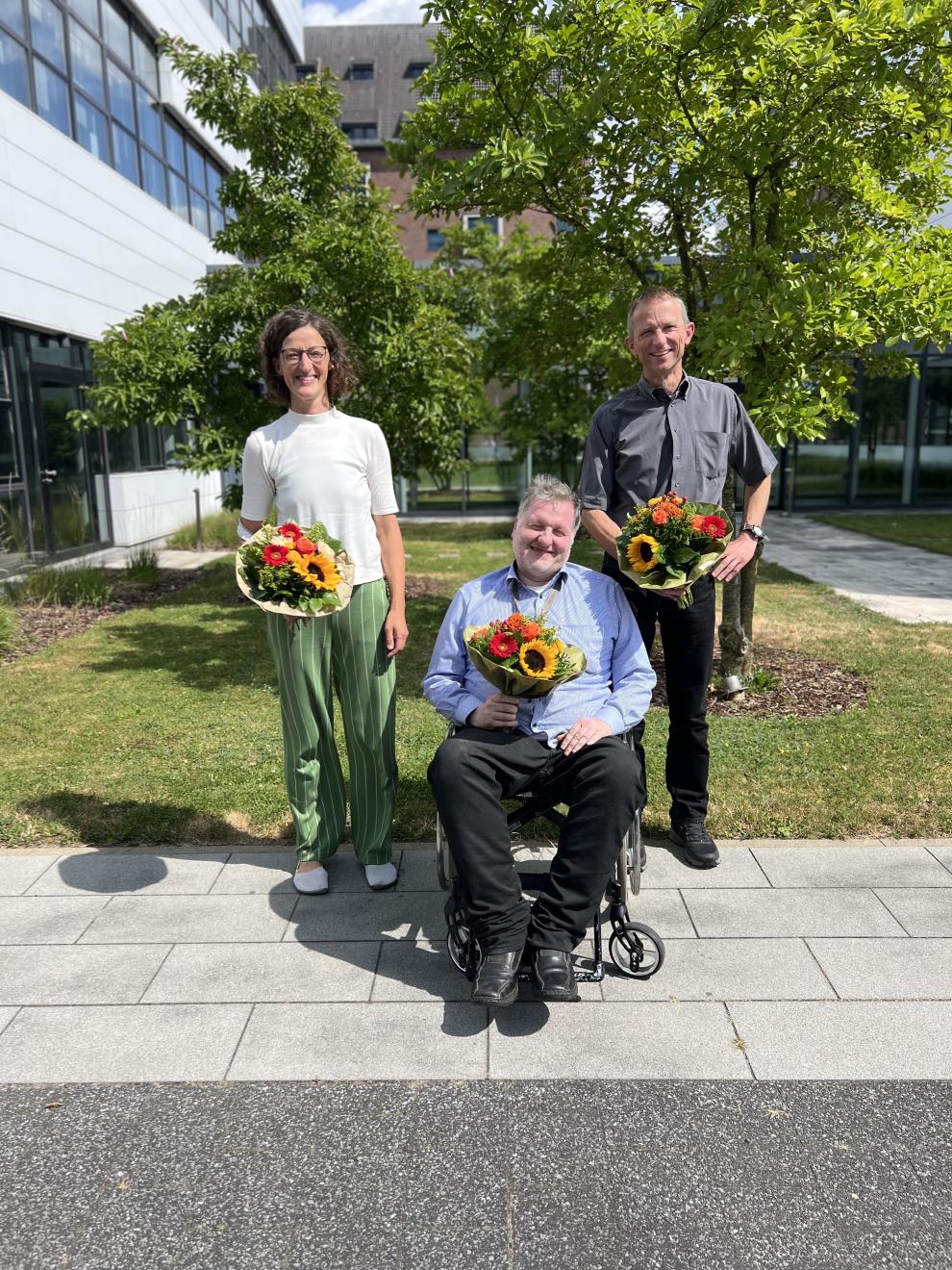 Dekanin Prof. PD Dr.-Ing. Sylvia Moenickes, Prodekan Prof. Dr.-Ing. Frank Platte und Studiendekan Prof. Dr. Peter F. W. Simon halten Blumen in der Hand und stehen vor den Gebäuden der Fakultät Life Science