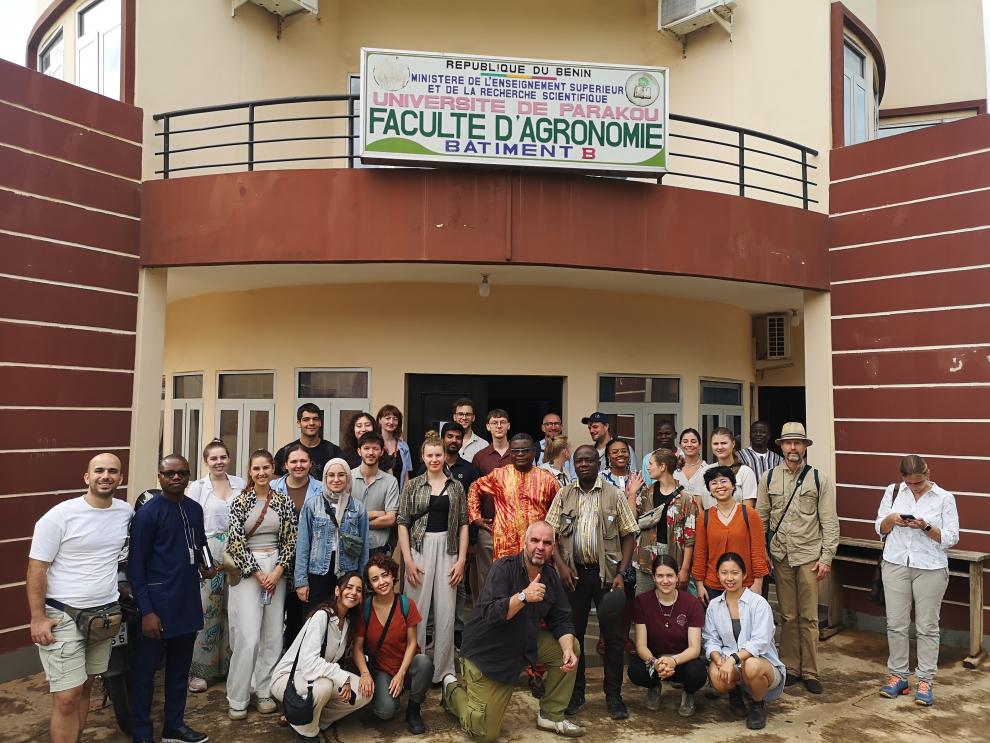 Die Exkursionsgruppe steht für ein Foto vor dem Eingang eines Universitätsgebäudes. Ein Schild über dem Eingang trägt die Aufschrift "Université de Parakou - Faculté d'Agronomie".