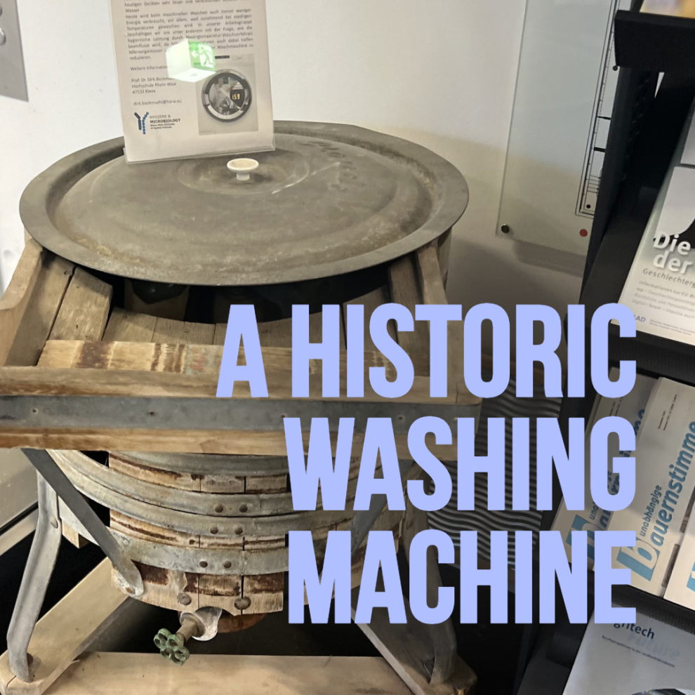 Historische Waschmaschine aus Holz aus der Mitte des 20. Jahrhunderts, bestehend aus einem hölzernen Bottich auf einem Gestell mit Metalldeckel.