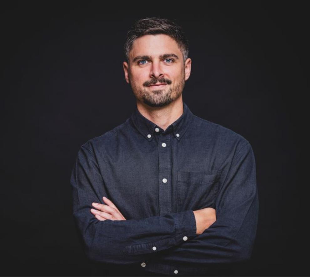 Ein Herr steht vor schwarzem Hintergrund.