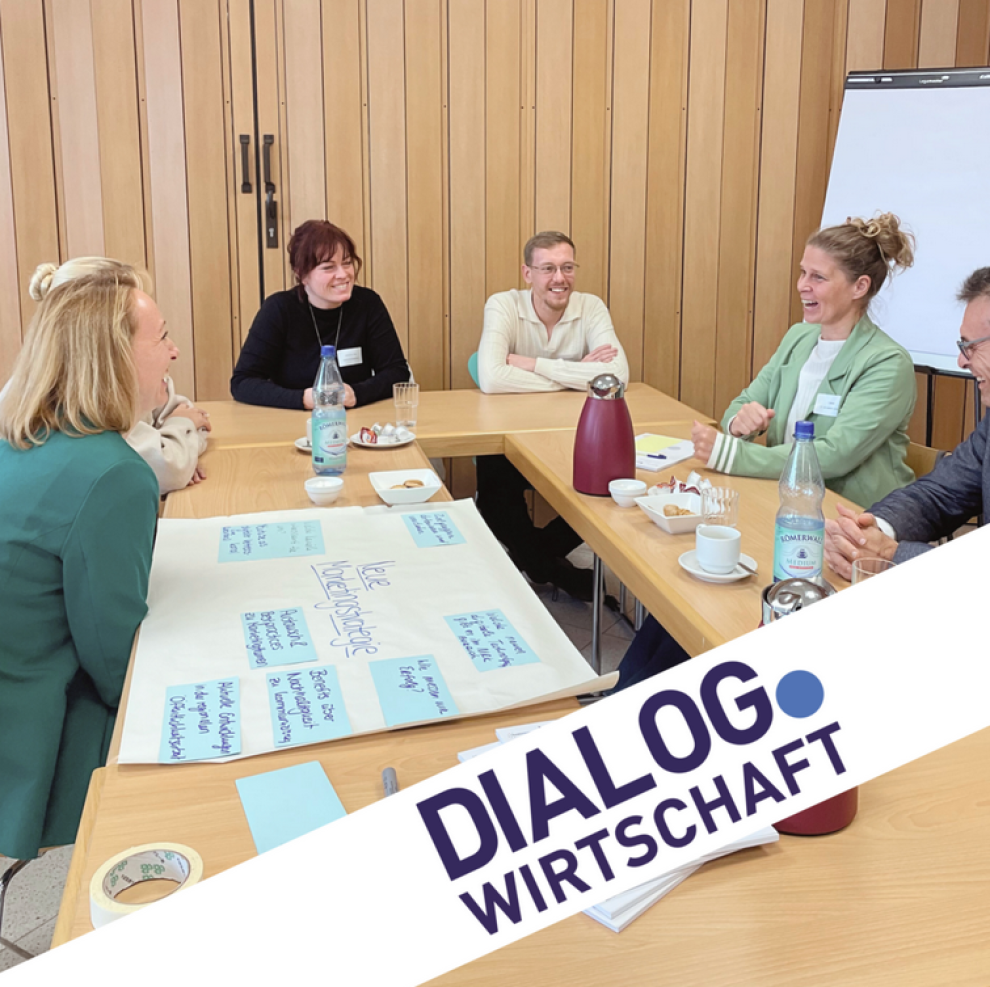 Mehrere Personen sitzen an einem Tisch und sprechen miteinander.