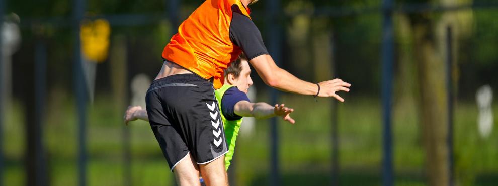 Junger Mann fängt im Sprung einen gelben Frisbee.